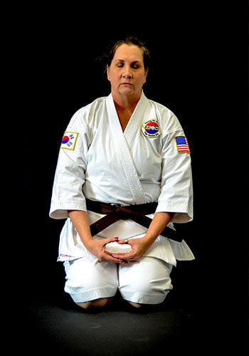 Molly Marie kneeling in her Tae Kwon Do uniform. She is in a meditative state with her eyes closed and hands resting in her lap.